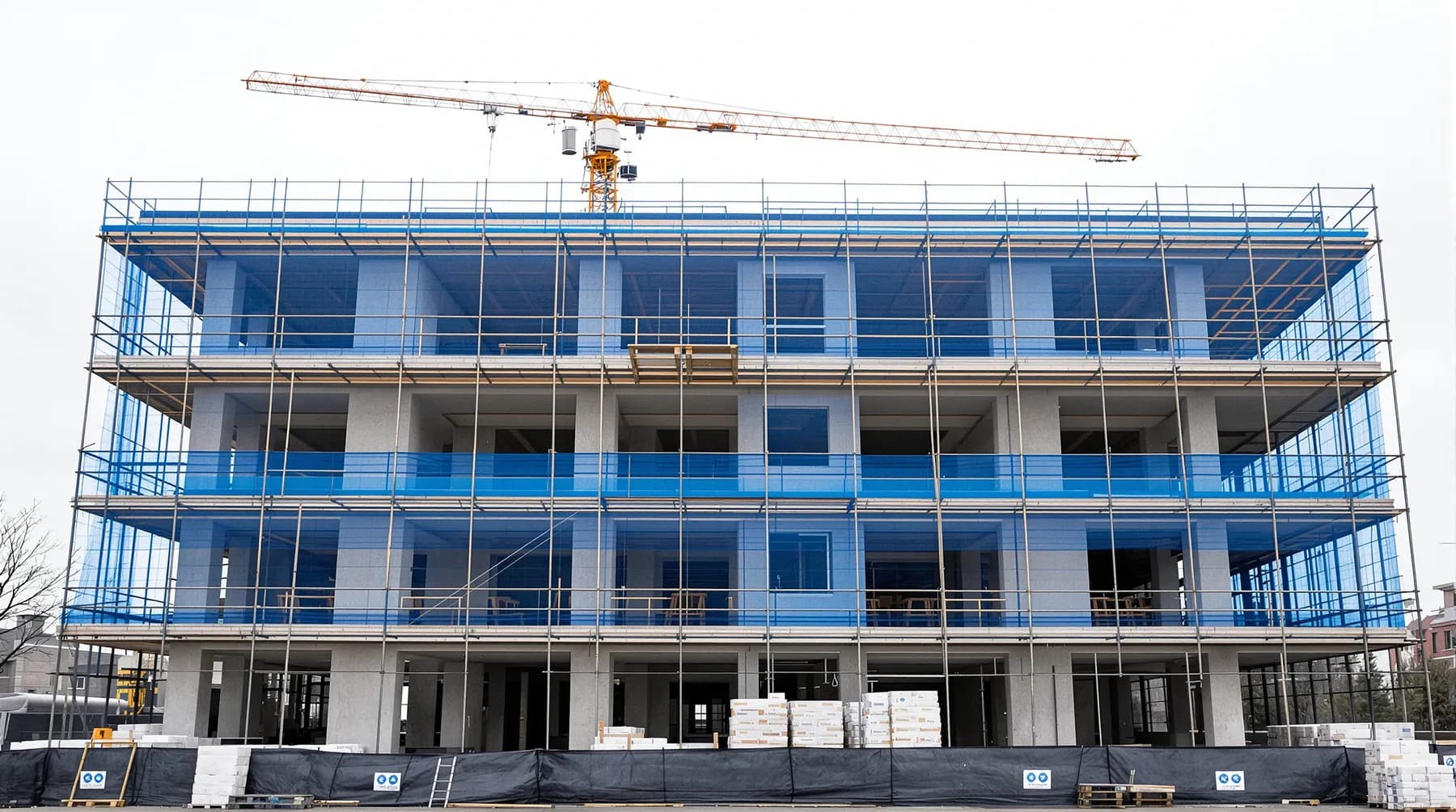 Nyproducerat bostadshus under byggnation med betongstomme och blå ställningsväv