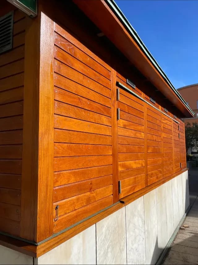 Nylackad träpanelfasad i varm orange kulör mot klarblå himmel